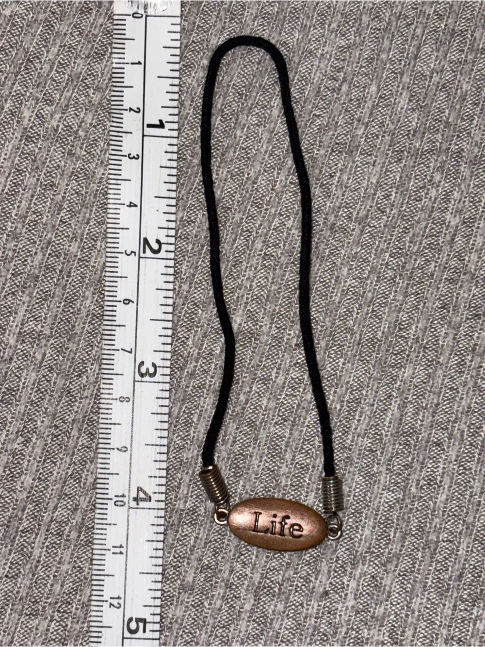 Black cord stretch bracelet w brown colored oval “Life” plaque